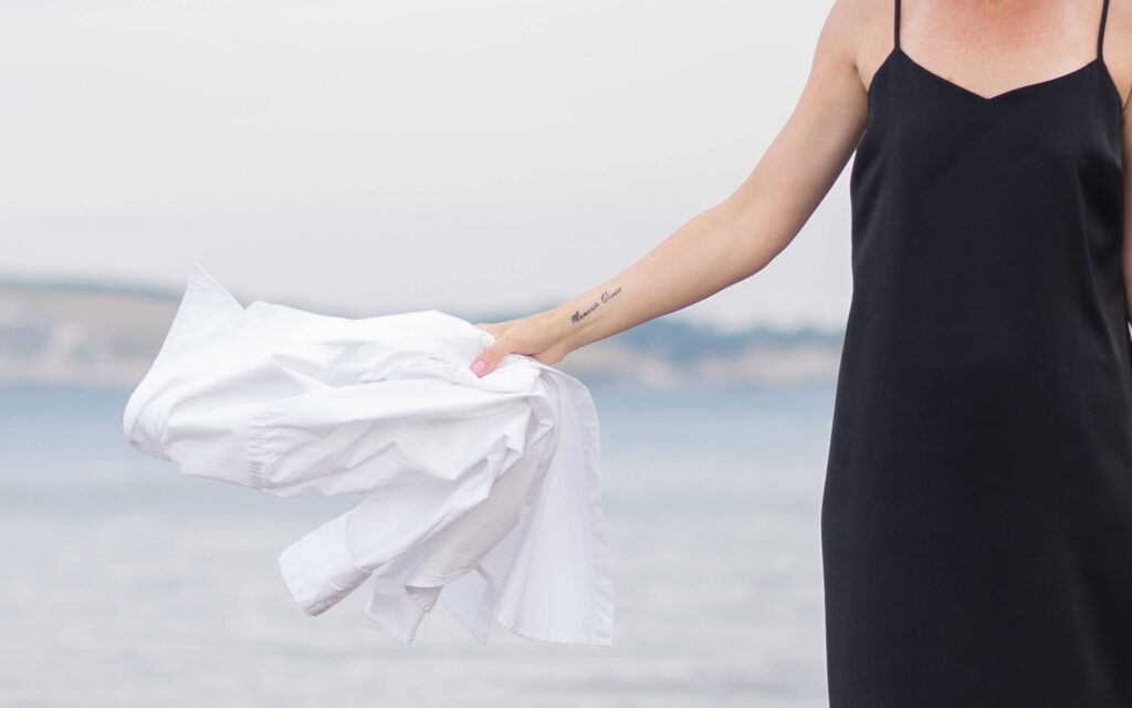 woman's portrait by the sea. she is holding a white shirt