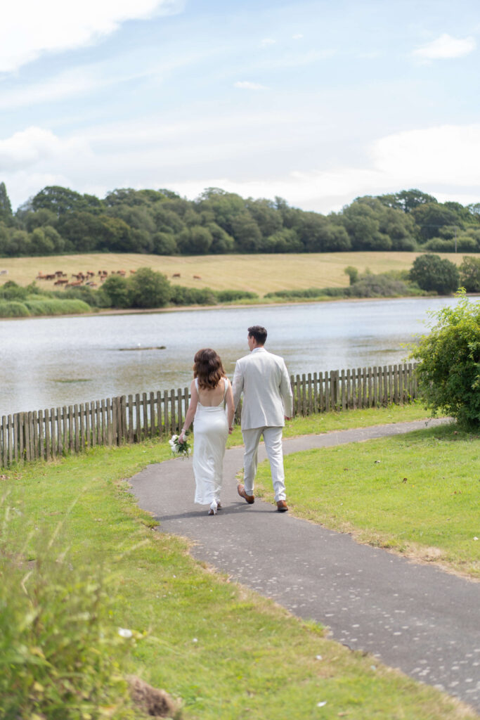 Bride and groom walking together by the lake