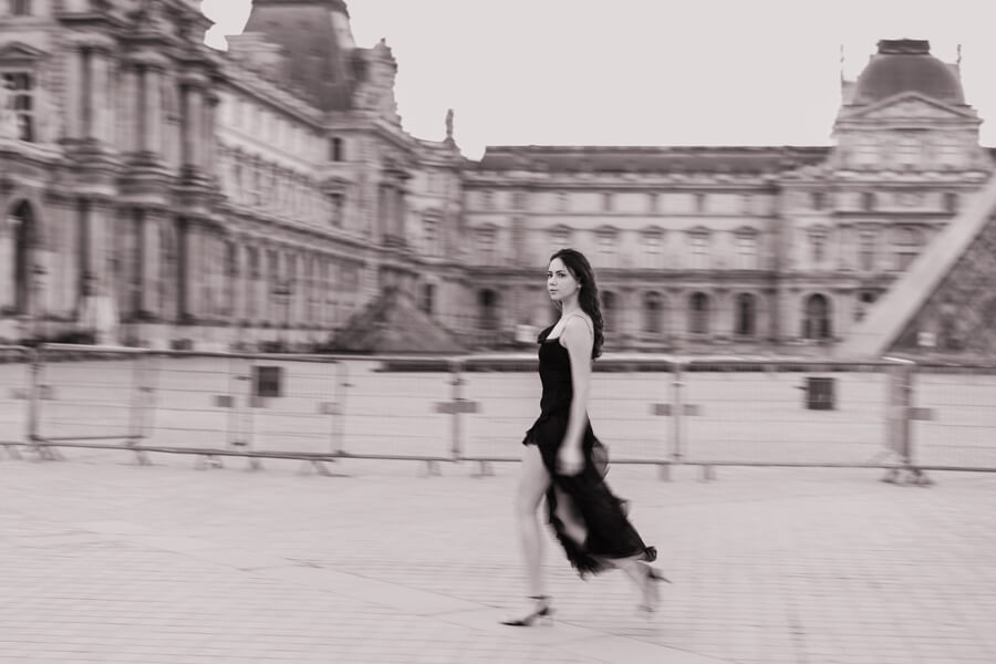 A portrait of a young woman is walking past the Louvre Museum 