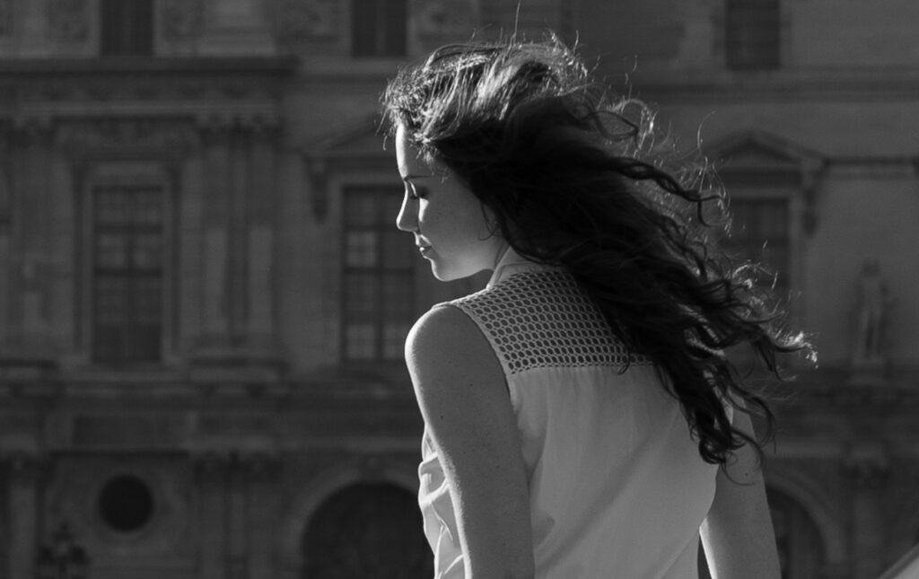 A black and white portrait of a young woman with sun in her hair