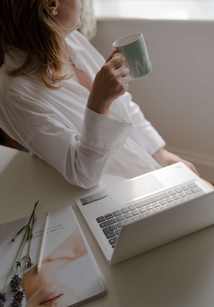 A women drinking coffee sitting in front of her laptop