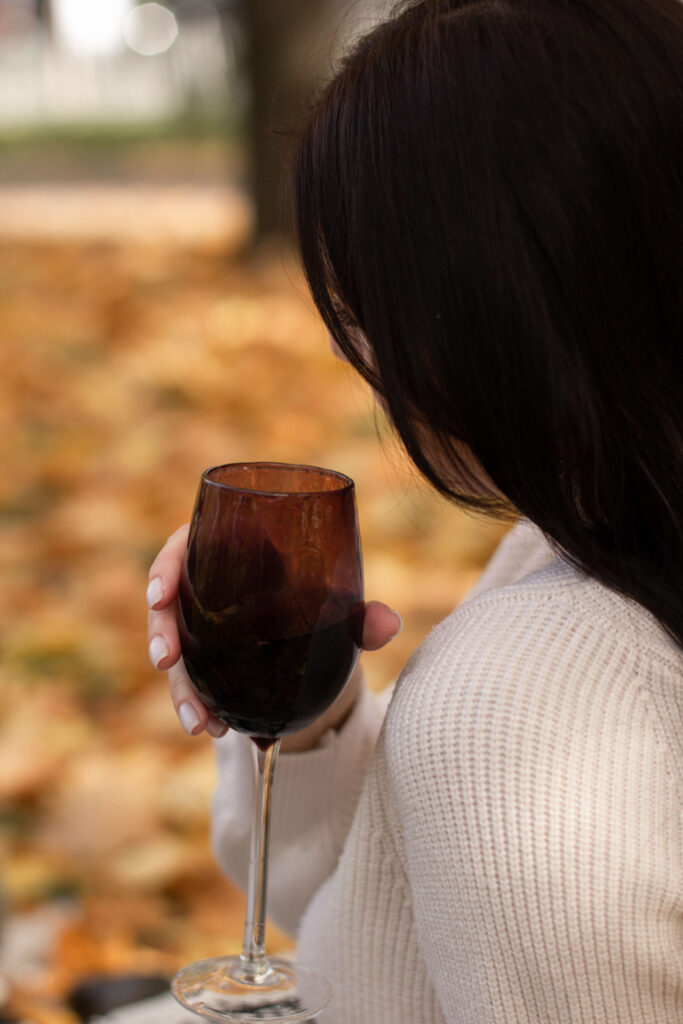 a woman holding a glass of wine in Autumn